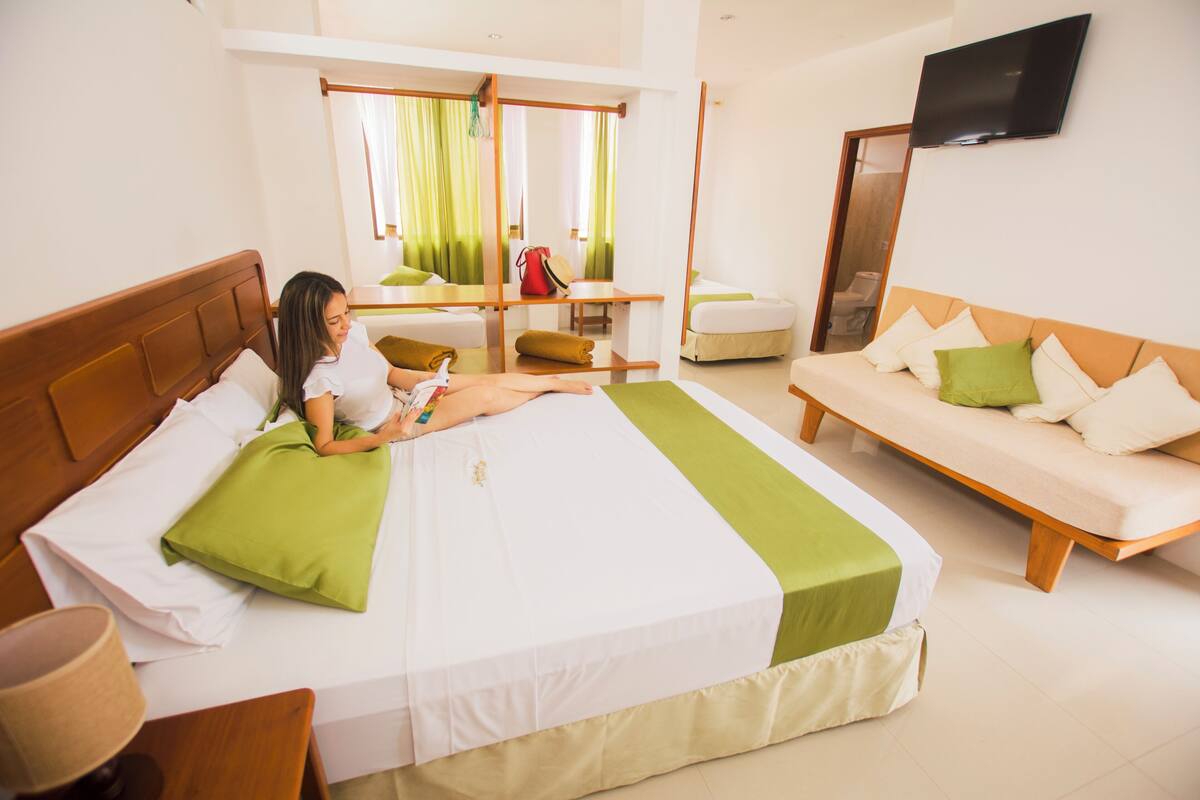 Une chambre d’hôtel avec un lit, un canapé, une télévision et un miroir.
