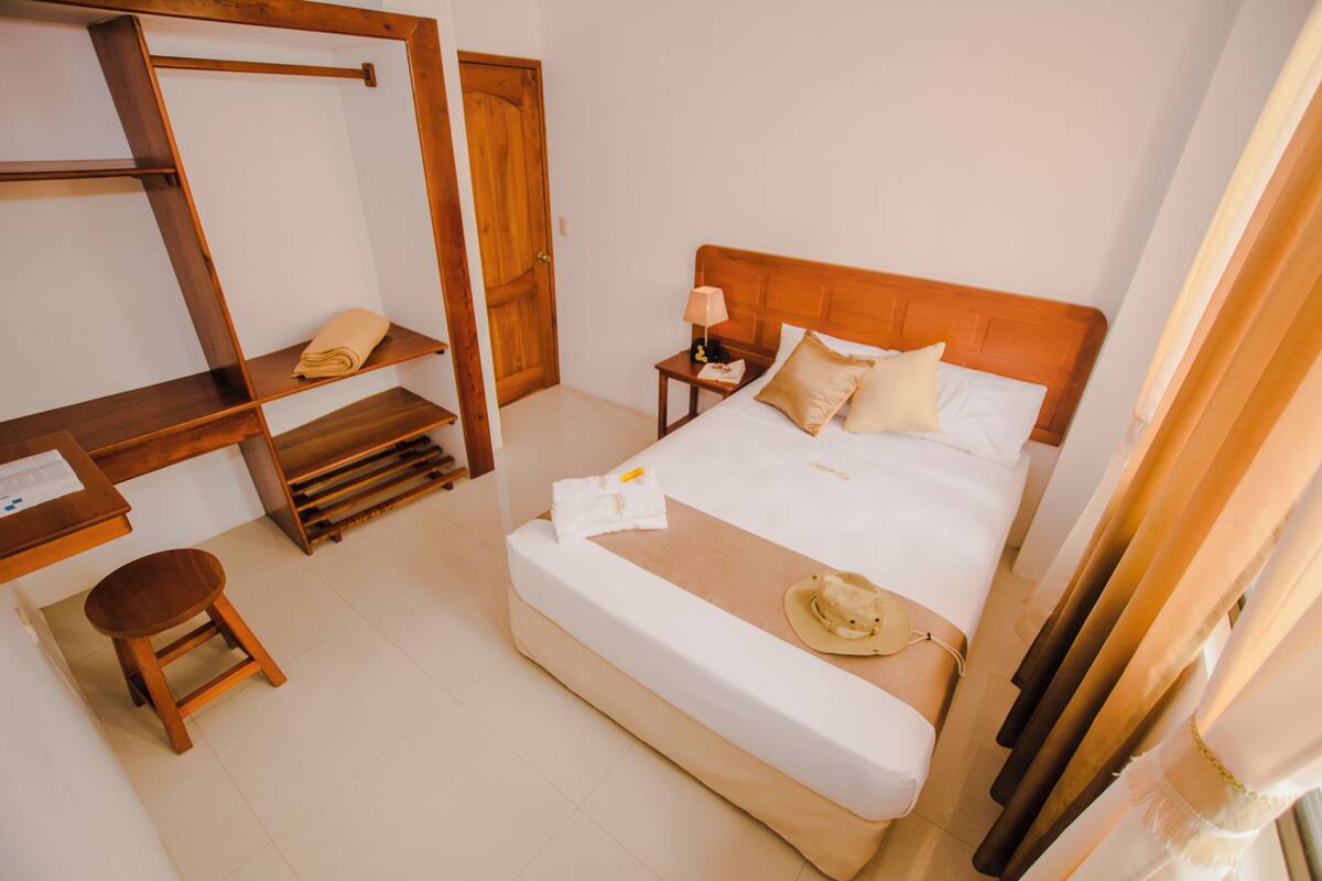 Une chambre d’hôtel avec un lit en bois, un bureau et une chaise.