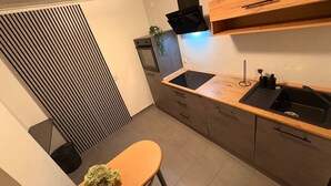 A modern kitchen with a wooden countertop, black sink, and built-in oven. - Studio One - 5 min to Grafenwöhr (Pressath)