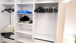 A walk-in closet with multiple shelves and hanging space, organized drawers, and a ceiling light fixture. - cozy & 5 min. From Cairo airport

 (Cairo Governorate)