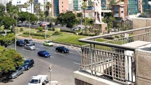 A modern building complex with multiple high-rise structures, a central statue, and a well-maintained road with parked cars. - cozy & 5 min. From Cairo airport

 (Cairo Governorate)