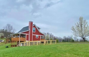 A red house with a balcony, surrounded by a fenced yard.