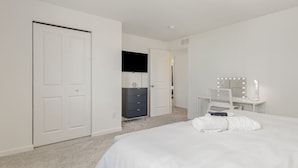 A bedroom with a bed, a dresser, a vanity with mirrors, and a door. - Brand New House with Hot Tub! Gameroom! Workspace! (Michigan City)