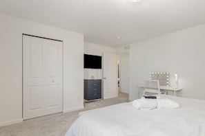 Une chambre à coucher comprenant un lit, une commode, une coiffeuse avec des miroirs et une porte.