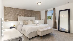 Une chambre à coucher avec un grand lit, une table de chevet, un miroir et une fenêtre avec des rideaux.