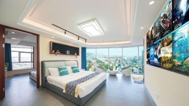 A modern hotel room with a large bed, a view of the city, and a wall with movie posters. - Tujia Sweetome Vacation Rentals (Middle Xianggang Road Lijing Yuzhu) (Qingdao)