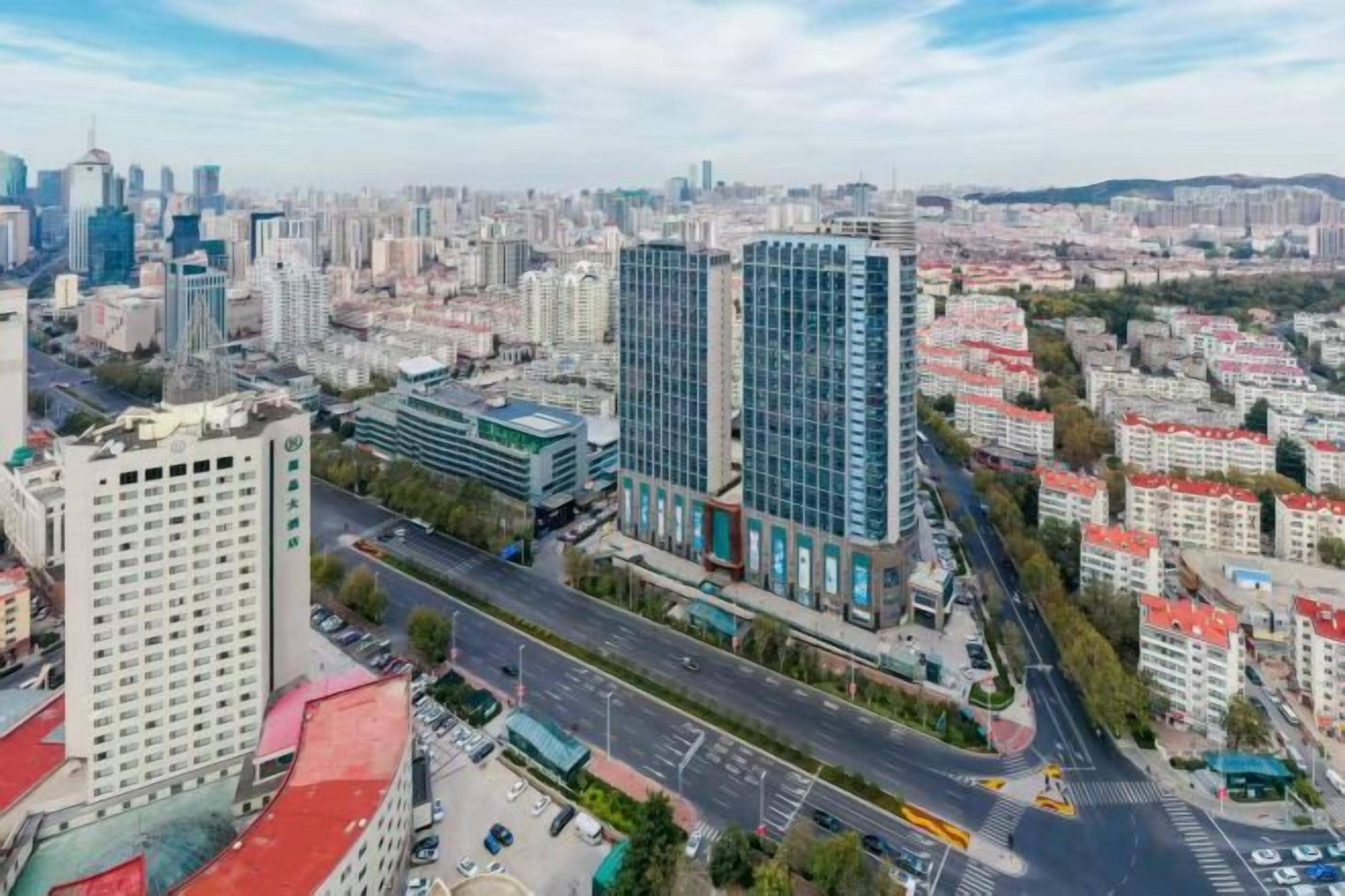 Un paisaje urbano con edificios modernos, una intersección vial destacada y una combinación de edificios altos y bajos.