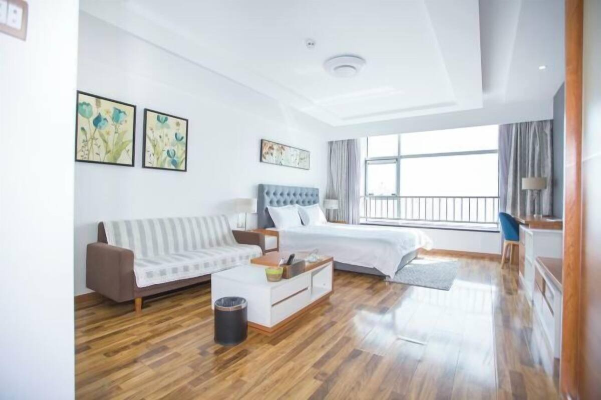 A modern hotel room with a bed, a sofa, a coffee table, and artwork on the walls.