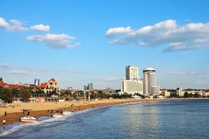 A coastal cityscape with a beach, boats, and high-rise buildings. - Tujia Sweetome Vacation Rentals (Middle Xianggang Road Lijing Yuzhu) (Qingdao)