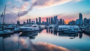 A marina with several yachts docked, reflecting a city skyline in the background. - Tujia Sweetome Vacation Rentals (Middle Xianggang Road Lijing Yuzhu) (Qingdao)
