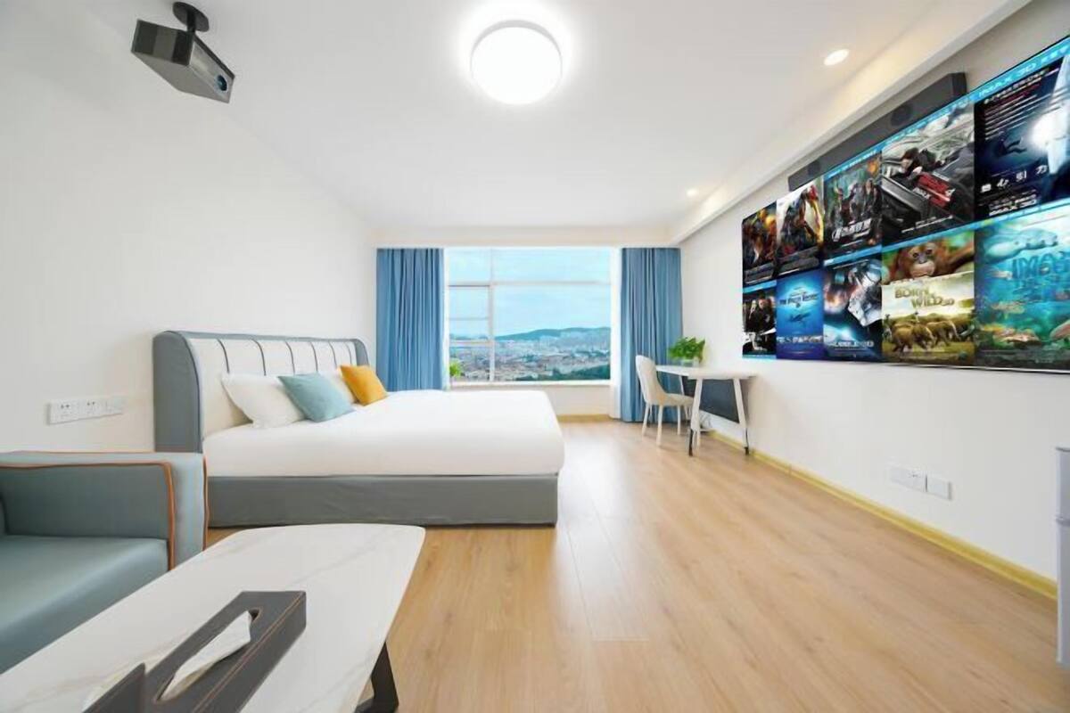 A modern hotel room with a large bed, a desk, and a wall-mounted TV.