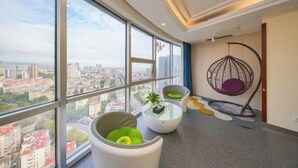 A modern room with large windows, a hanging chair, and a small table with a plant. - Tujia Sweetome Vacation Rentals (Middle Xianggang Road Lijing Yuzhu) (Qingdao)