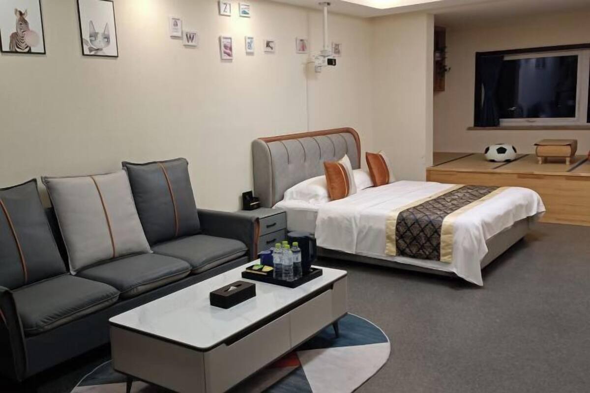 A hotel room with a bed, a sofa, a coffee table, and a TV.