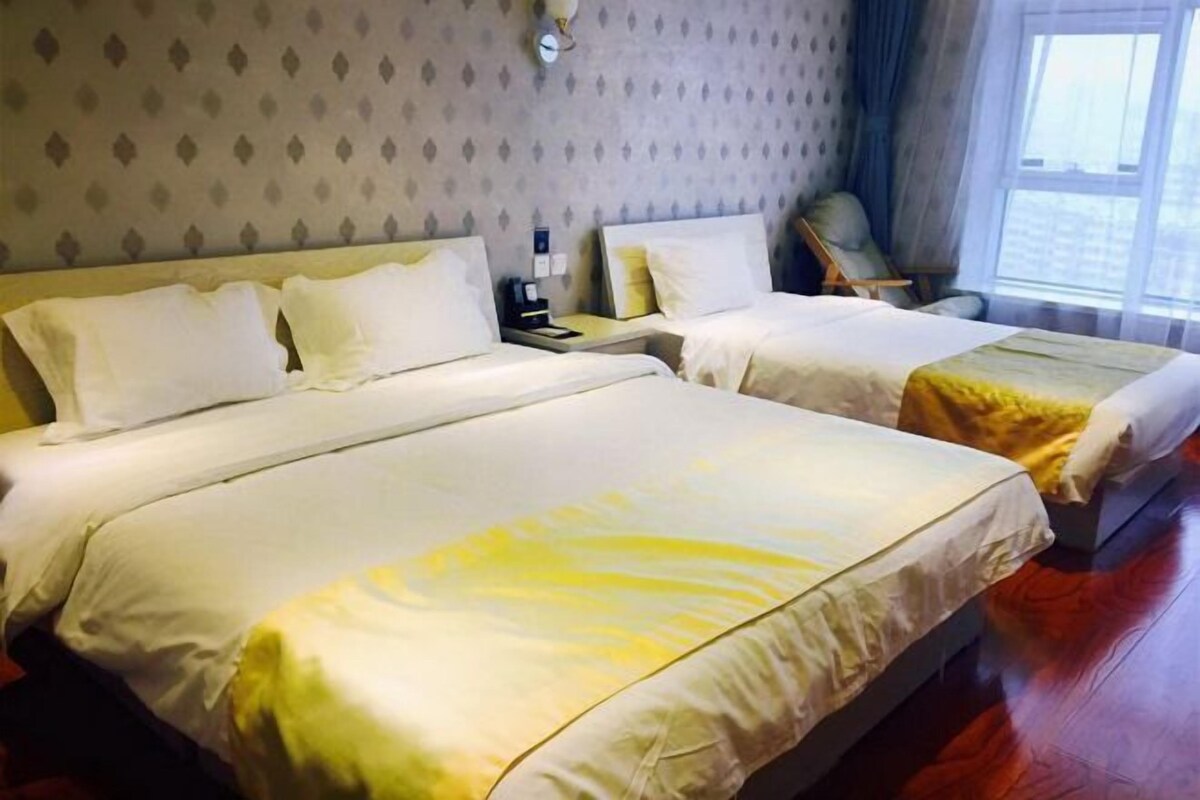 A hotel room with two beds, a nightstand, a chair, and a window with a view.