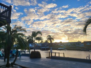 Un paseo marítimo con palmeras, zonas de descanso y embarcaciones amarradas al fondo.
