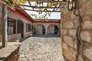 A courtyard with stone walls, wooden beams, and potted plants.