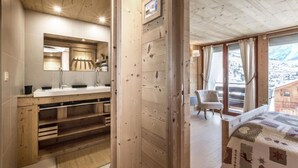 A wooden interior with a bathroom, a bed, and a view of the outside. - 70m from ski slopes, Ground floor, balcony, fireplace or stove, tv, ski locker, 74m², La Clusaz (La Clusaz)