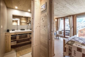 Interior de madera con baño, cama y vistas al exterior.