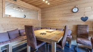 A wooden-paneled room with a round table, leather chairs, a bench, a clock, and a heart-shaped decoration. - 70m from ski slopes, Ground floor, balcony, fireplace or stove, tv, ski locker, 74m², La Clusaz (La Clusaz)