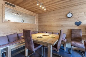 Una habitación con paneles de madera, una mesa redonda, sillas de cuero, un banco, un reloj y una decoración con forma de corazón.