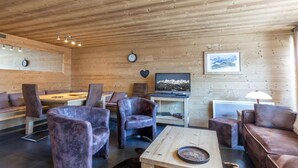A wooden interior with a dining area, seating, a television, and a clock. - 70m from ski slopes, Ground floor, balcony, fireplace or stove, tv, ski locker, 74m², La Clusaz (La Clusaz)