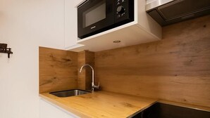 A kitchen with a wooden countertop, stainless steel sink, and a microwave above the counter.
