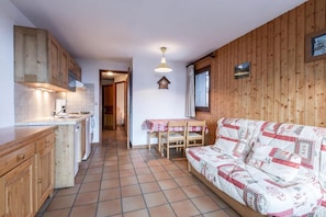 Ein gemütliches Blockhaushaus-Interieur mit Küchenzeile, Essbereich und Wohnbereich mit Sofa.