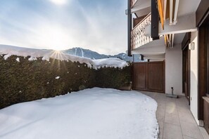 A snow-covered courtyard with a wooden fence, a balcony with wooden railings, and a view of mountains in the background. - 250m from ski slopes, Ground floor, terrace, tv, ski locker, 28m², La Clusaz (La Clusaz)