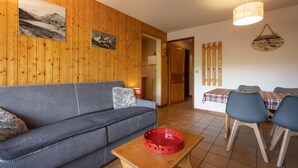 Un accogliente soggiorno con un divano, un tavolo da pranzo con sedie e pareti in legno.