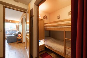 Habitación compacta con literas, una mesita con lámpara, un sofá y vistas al exterior.