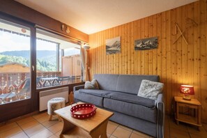 Una sala de estar acogedora con un sofá gris, una mesita de madera y una bandeja roja con estampado de corazones.