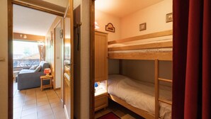 Una camera compatta con un letto a castello, un piccolo tavolo con lampada, un divano e vista sull'esterno.