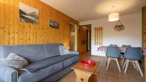 Un accogliente soggiorno con un divano, un tavolo da pranzo con sedie, pareti in legno e un lampadario.