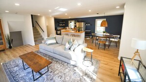 A modern living room with a sofa, coffee table, and dining area. - 5 STAR Coastal Farmhouse- Dog Friendly- 3BR in Westerly! Minutes to Beach & Town (Westerly)