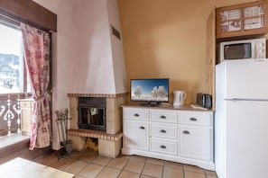 Eine kompakte Küche mit integriertem Kamin, einem Fernseher und einem Kühlschrank.