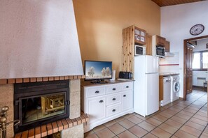 A kitchen with a fireplace, a microwave, a washing machine, and a television.