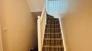 Eine Treppe mit Streifenmuster-Teppich und weißen Geländern.