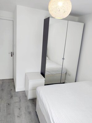 Ein Schlafzimmer mit Bett, Kleiderschrank und einer Pendelleuchte.