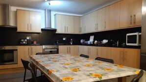 Eine moderne Küche mit Holzausstattung, einem Esstisch mit Blumenmuster-Tischdecke und einer Mikrowelle.