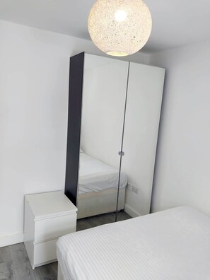 Ein schlichter Schlafzimmer mit Bett, Kleiderschrank und Nachttisch.