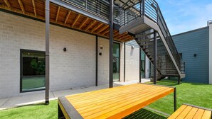 A modern building with a brick facade, a wooden deck, and a metal staircase.