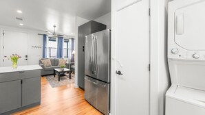 A modern kitchen with a stainless steel refrigerator, a built-in oven, and a washing machine.