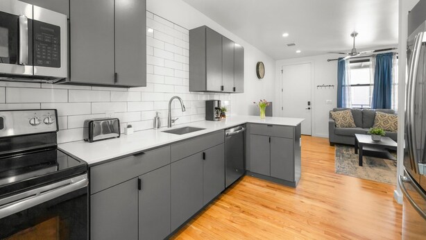 A modern kitchen with grey cabinets, a stainless steel microwave, and a toaster.