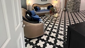 A living room with a sofa, a coffee table, and a television. The floor has a black and white geometric pattern. - Frida Unit #2. Charming 2-bedroom apartment  in delightful Corpus Christi. (Corpus Christi)