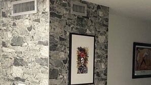 A corner of a room with a stone wall, a framed artwork, and a vent. - Frida Unit #2. Charming 2-bedroom apartment  in delightful Corpus Christi. (Corpus Christi)