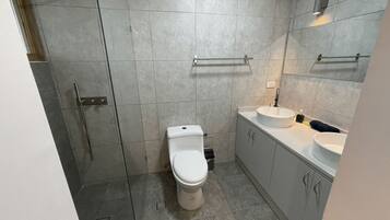 Un bany modern amb vàter, rentapel i plat de dutxa.