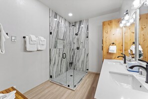 A modern bathroom with a glass-enclosed shower, a wooden vanity with a mirror, and a white sink. - St8709-3 (Keystone)