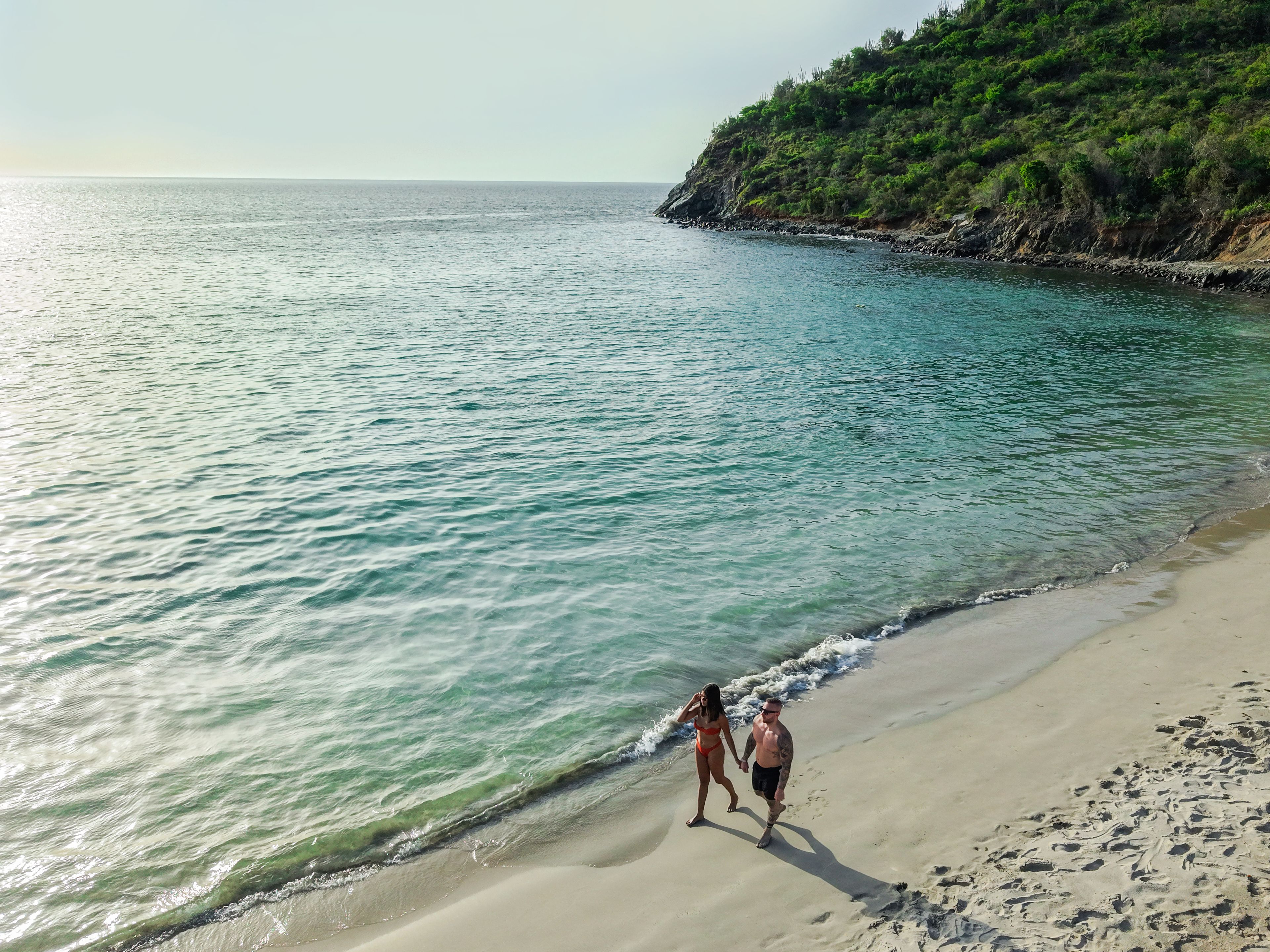 A beach with clear water and a sandy shore.