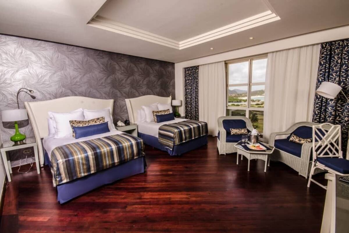 Ein Hotelzimmer mit zwei Betten, einer Sitzecke mit Tisch und Blick ins Freie.