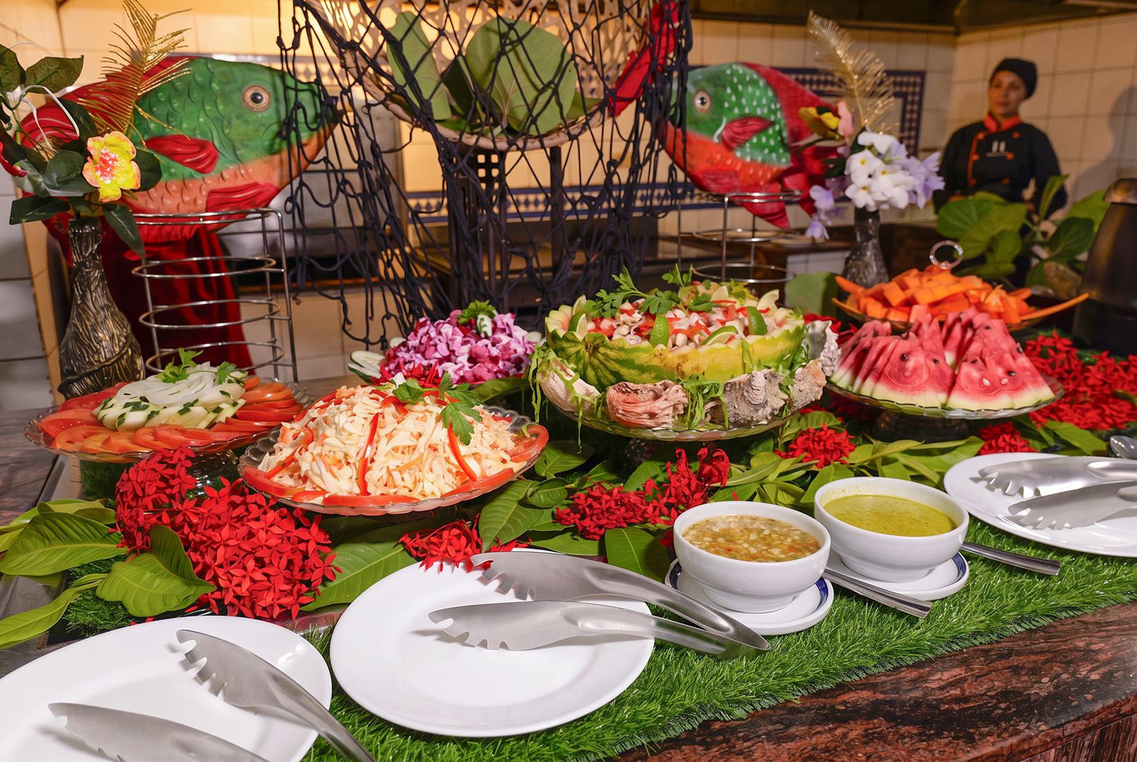A buffet table with various dishes and a decorative fish sculpture.